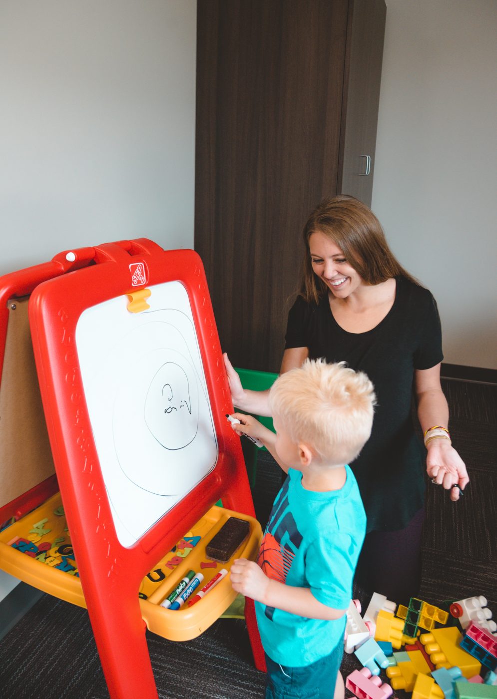 child writing on white board with therapist