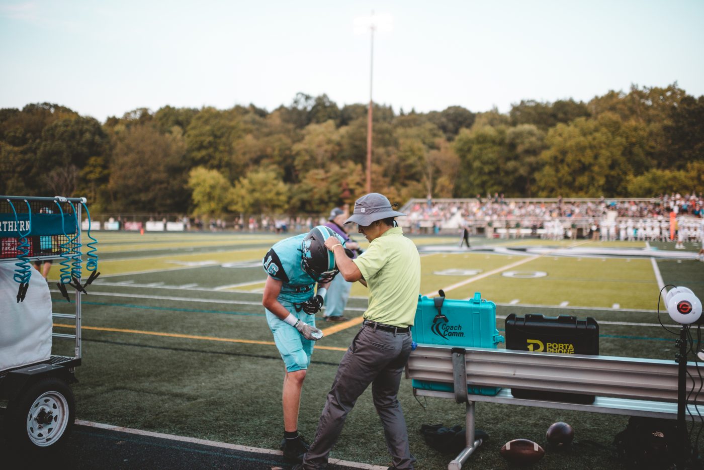 athletic trainer helping football player with helmet