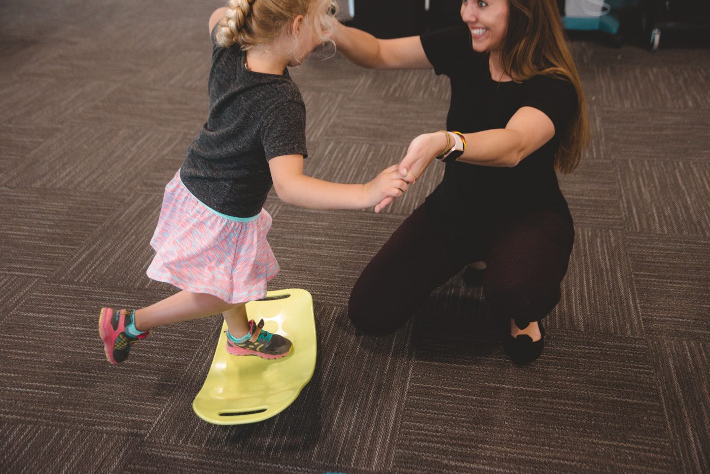 Child balancing on balance board with assistance